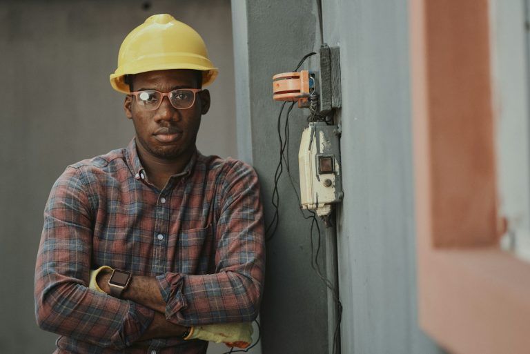 man in blue white and red plaid button up shirt wearing yellow hard hat holding black